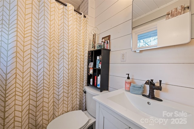 bathroom with vanity, a shower with shower curtain, toilet, and wood walls