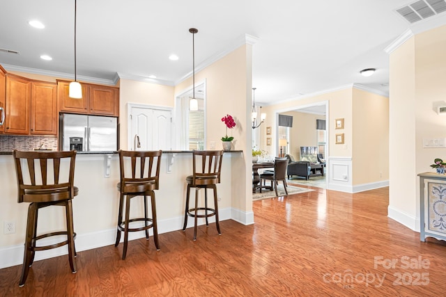 kitchen featuring pendant lighting, stainless steel fridge with ice dispenser, and a breakfast bar area