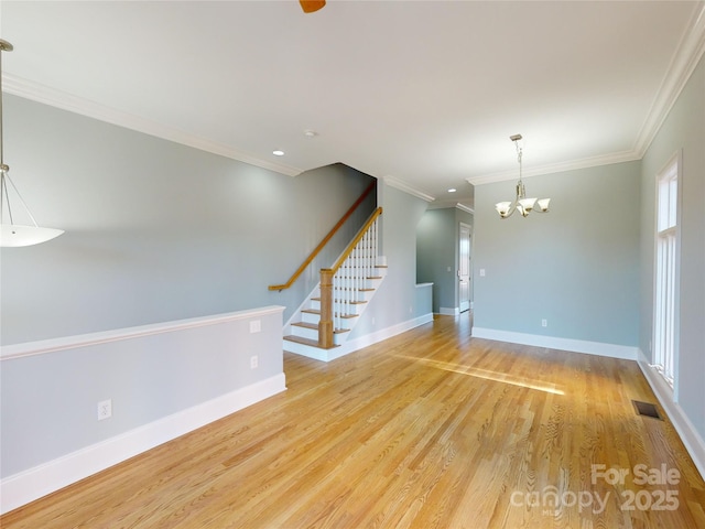 empty room featuring ornamental molding, a chandelier, and light wood-type flooring