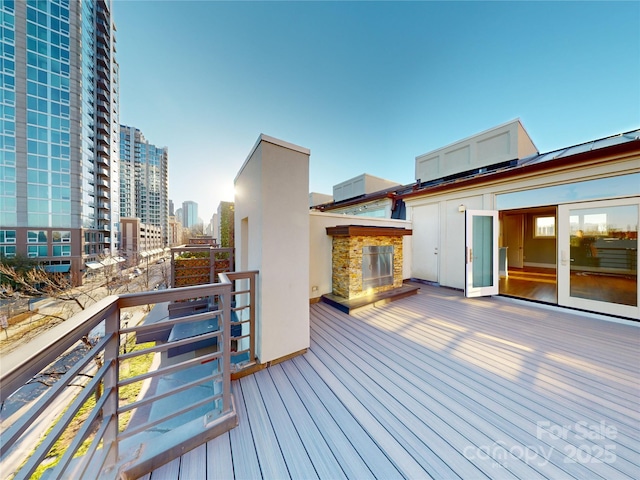 wooden deck featuring an outdoor stone fireplace