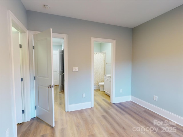 unfurnished bedroom featuring ensuite bathroom and light hardwood / wood-style floors