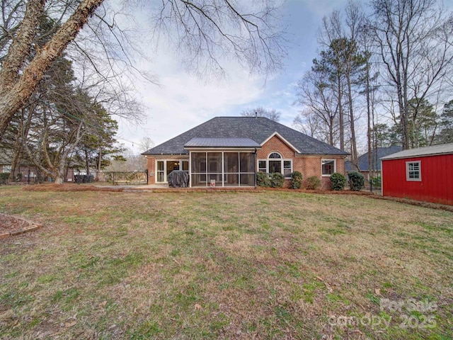 rear view of property with a lawn and a sunroom