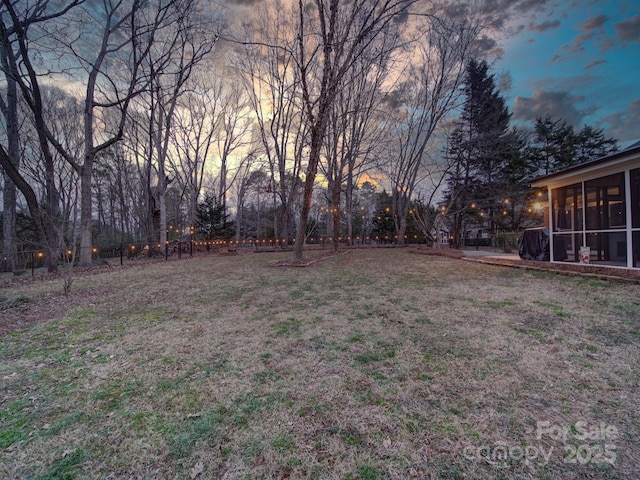 yard at dusk featuring a sunroom