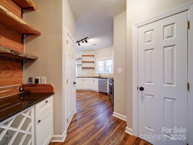 interior space with sink, dark wood-type flooring, dishwasher, dark stone countertops, and white cabinets