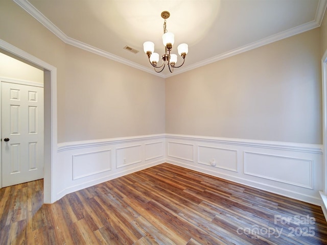 unfurnished room featuring dark hardwood / wood-style flooring, ornamental molding, and a chandelier