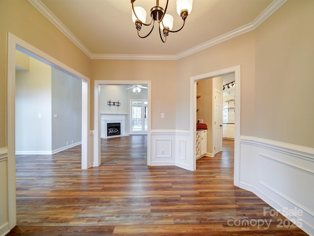 unfurnished dining area with crown molding, ceiling fan with notable chandelier, and dark hardwood / wood-style flooring