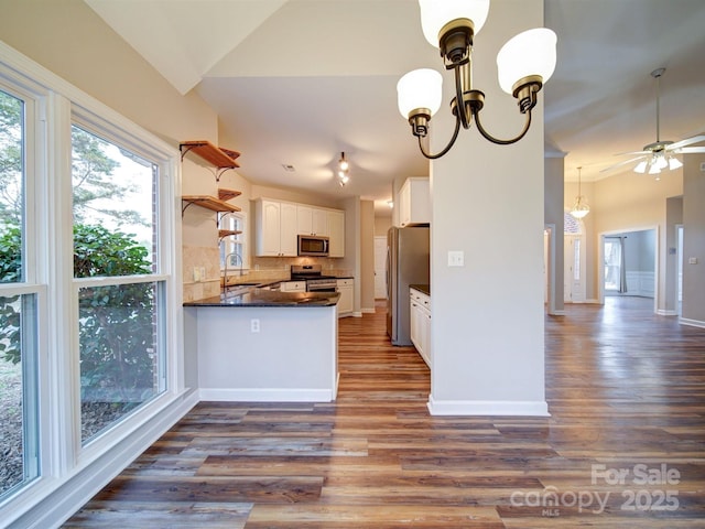 kitchen featuring vaulted ceiling, white cabinetry, hanging light fixtures, kitchen peninsula, and stainless steel appliances