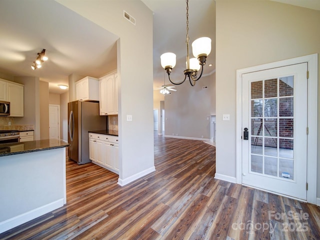 kitchen with white cabinetry, appliances with stainless steel finishes, dark hardwood / wood-style floors, and decorative light fixtures