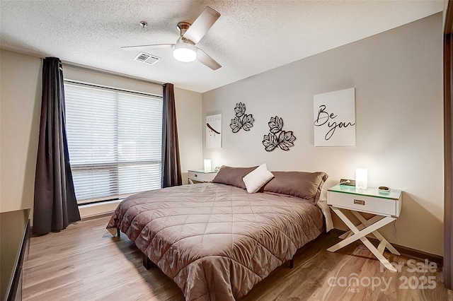 bedroom with ceiling fan, a textured ceiling, and light wood-type flooring