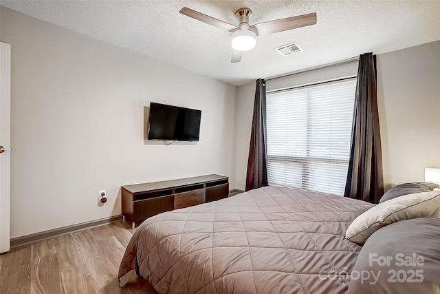 bedroom with ceiling fan, a textured ceiling, and light wood-type flooring