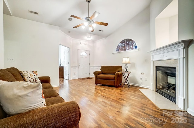 living room with ceiling fan, a fireplace, high vaulted ceiling, and light wood-type flooring