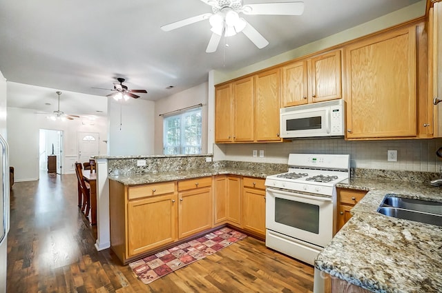 kitchen featuring dark hardwood / wood-style flooring, white appliances, kitchen peninsula, and decorative backsplash