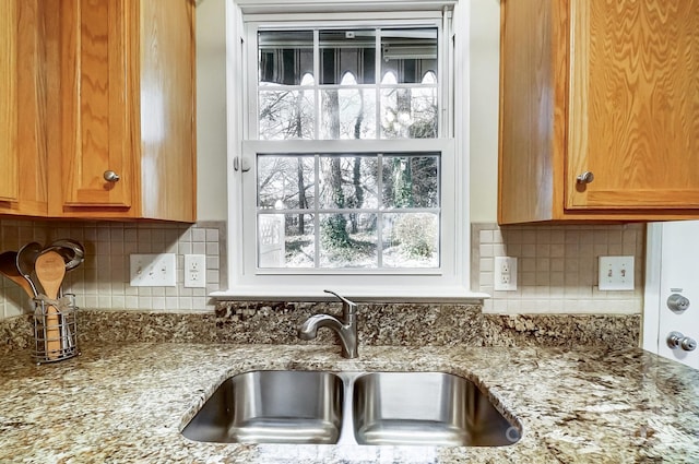 interior details with light stone countertops, sink, and backsplash