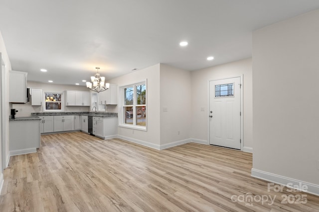 interior space featuring white cabinetry, dishwasher, light hardwood / wood-style floors, and hanging light fixtures