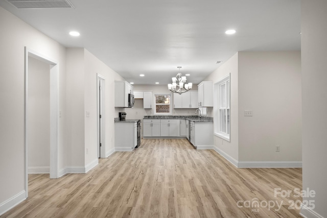 kitchen featuring sink, stainless steel electric range oven, a chandelier, light hardwood / wood-style floors, and white cabinets