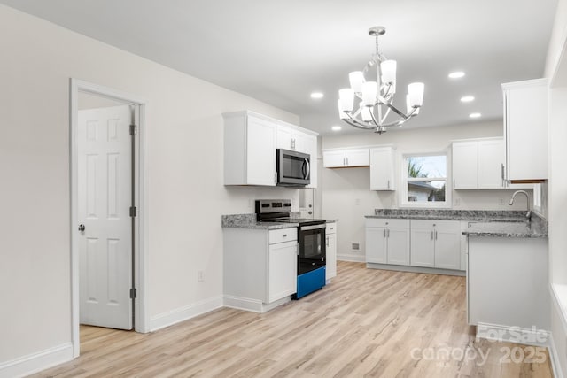 kitchen with light stone countertops, white cabinetry, appliances with stainless steel finishes, and light hardwood / wood-style floors