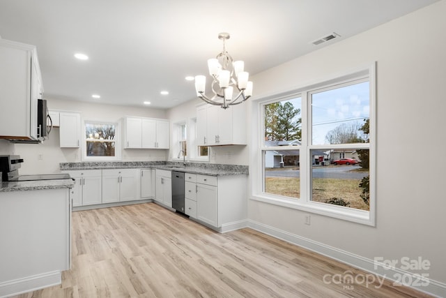 kitchen with pendant lighting, white cabinets, stainless steel appliances, light stone countertops, and light hardwood / wood-style flooring