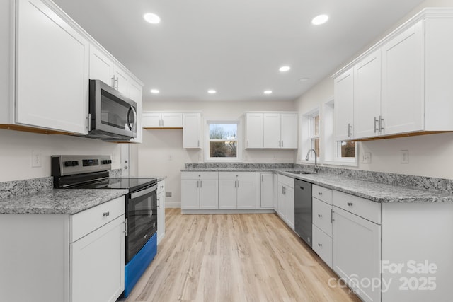 kitchen featuring sink, appliances with stainless steel finishes, light stone countertops, white cabinets, and light wood-type flooring