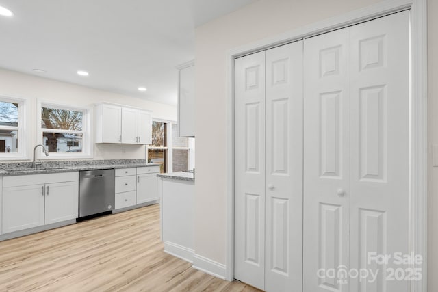 kitchen with dishwasher, sink, white cabinets, and light stone counters