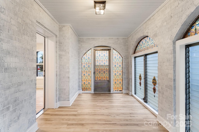 hallway featuring crown molding, brick wall, and light hardwood / wood-style floors