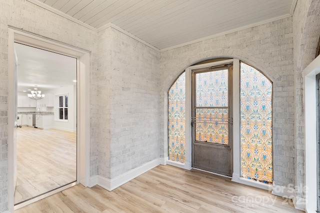 foyer with wood ceiling, crown molding, a chandelier, hardwood / wood-style flooring, and brick wall