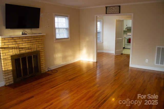 unfurnished living room featuring ornamental molding, hardwood / wood-style floors, and a brick fireplace