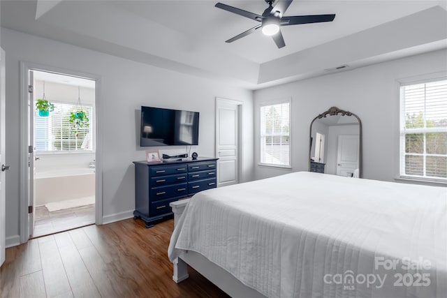 bedroom with ceiling fan, wood-type flooring, ensuite bathroom, and multiple windows