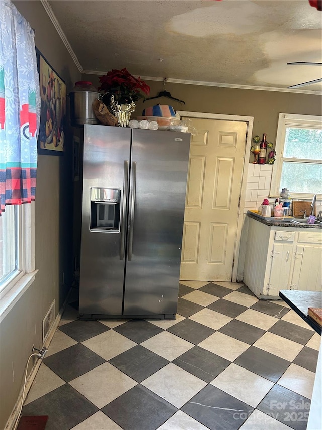 kitchen featuring white cabinetry, sink, crown molding, and stainless steel fridge