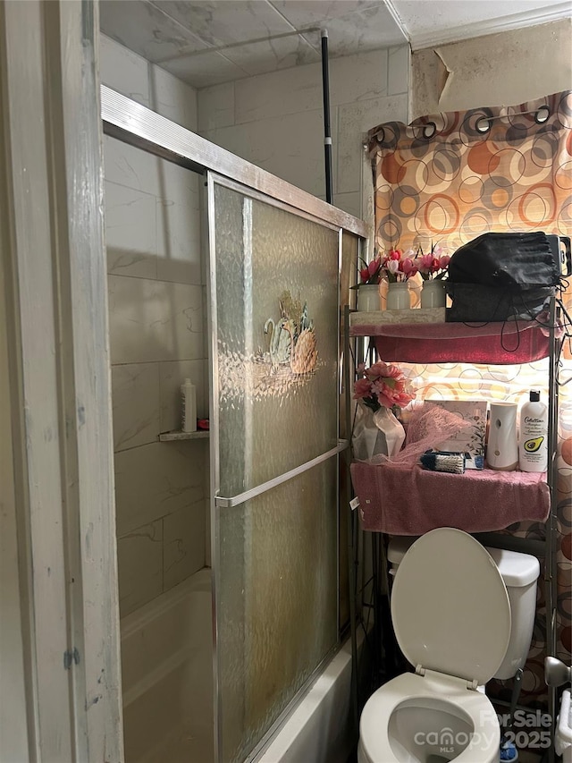 bathroom featuring shower / bath combination with glass door and toilet