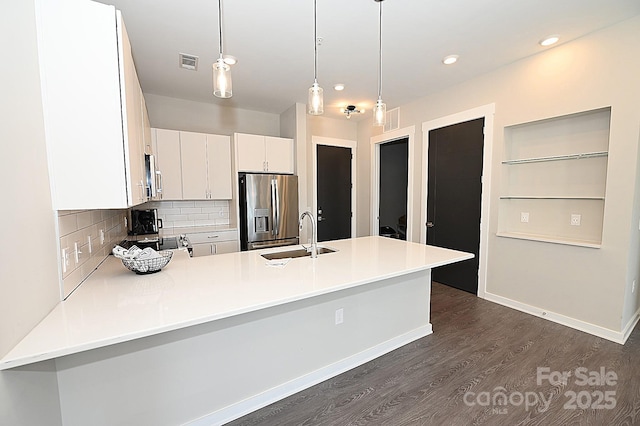 kitchen featuring dark hardwood / wood-style floors, decorative light fixtures, white cabinetry, sink, and stainless steel refrigerator with ice dispenser