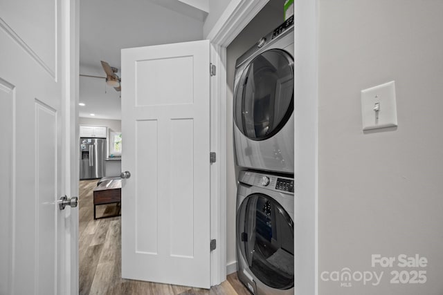 laundry room with light hardwood / wood-style flooring and stacked washer and clothes dryer