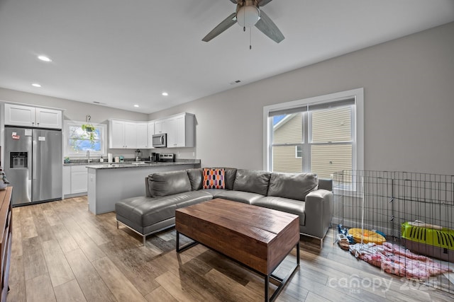 living room with ceiling fan, sink, and light hardwood / wood-style flooring