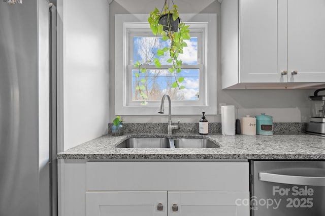 kitchen with light stone countertops, appliances with stainless steel finishes, sink, and white cabinets