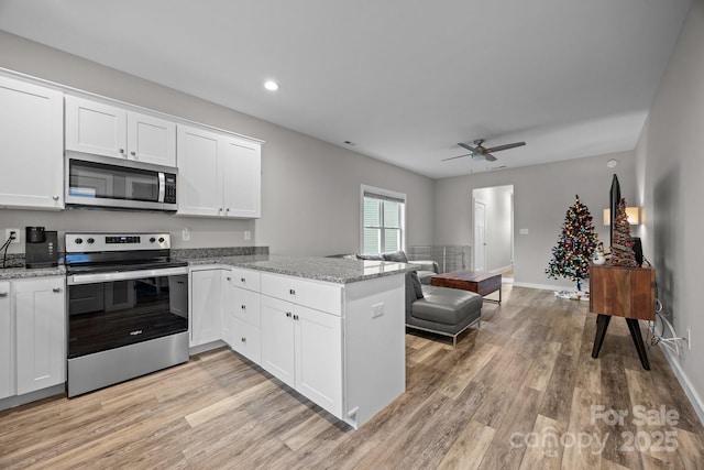 kitchen with white cabinetry, appliances with stainless steel finishes, kitchen peninsula, and light stone counters