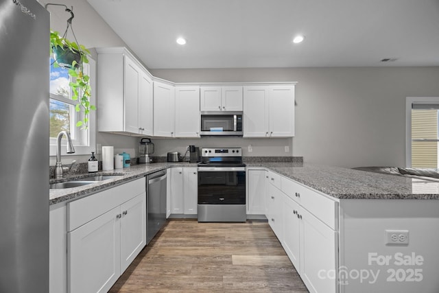 kitchen with white cabinetry, appliances with stainless steel finishes, kitchen peninsula, and sink