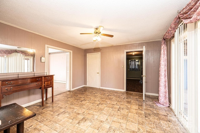 unfurnished room featuring ceiling fan, crown molding, wooden walls, and a textured ceiling