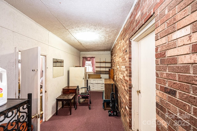 hall featuring brick wall, a textured ceiling, and dark carpet