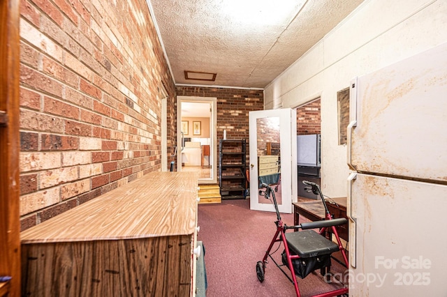 corridor featuring brick wall, dark carpet, and a textured ceiling