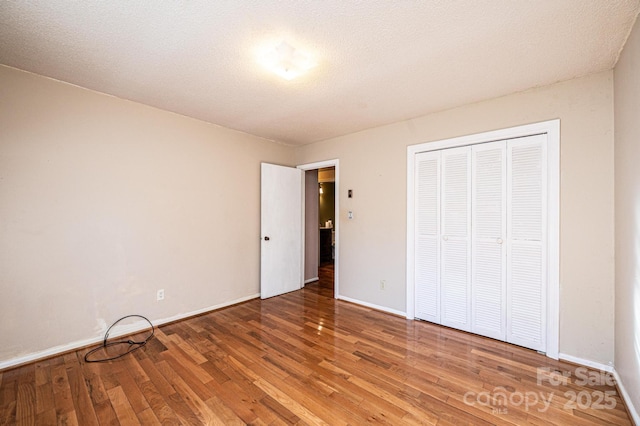 unfurnished bedroom with hardwood / wood-style flooring, a textured ceiling, and a closet