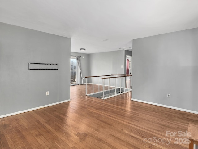 spare room featuring baseboards and wood finished floors