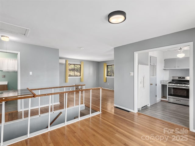 unfurnished room featuring light wood-style floors, visible vents, baseboards, and a wall mounted AC
