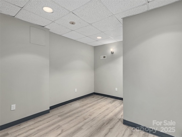 spare room featuring a drop ceiling, wood finished floors, visible vents, and baseboards