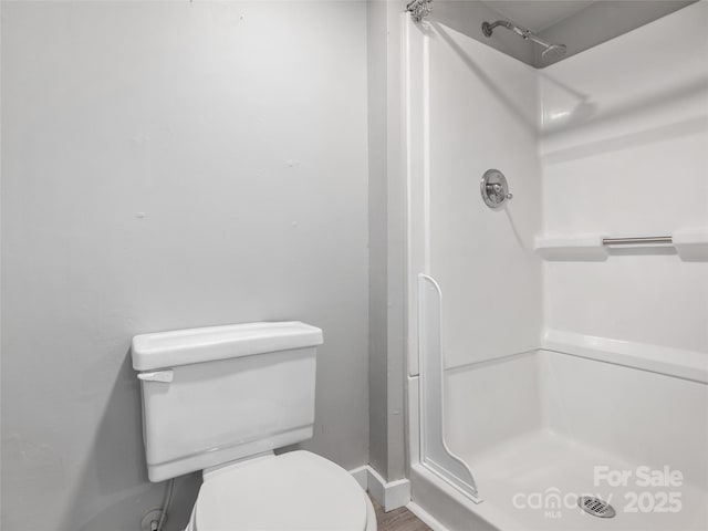 bathroom with toilet, a stall shower, and baseboards