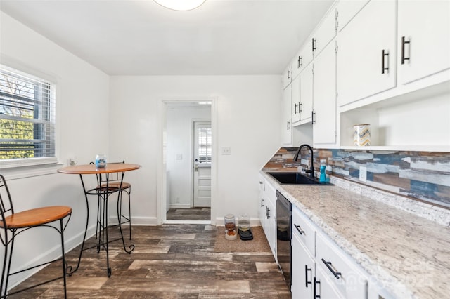 kitchen featuring sink, white cabinetry, dark hardwood / wood-style floors, black dishwasher, and light stone countertops