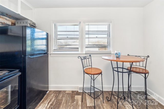 kitchen featuring electric stove, black fridge, and hardwood / wood-style flooring