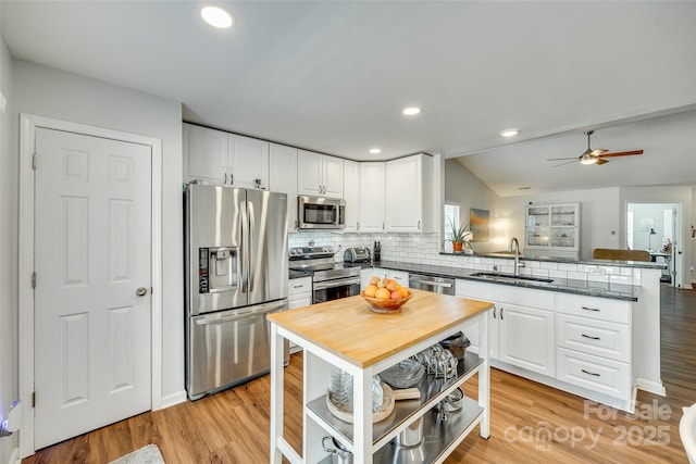 kitchen featuring sink, light wood-type flooring, appliances with stainless steel finishes, kitchen peninsula, and white cabinets