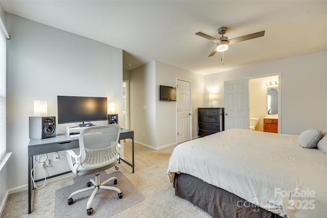 bedroom featuring ceiling fan, light colored carpet, and ensuite bath