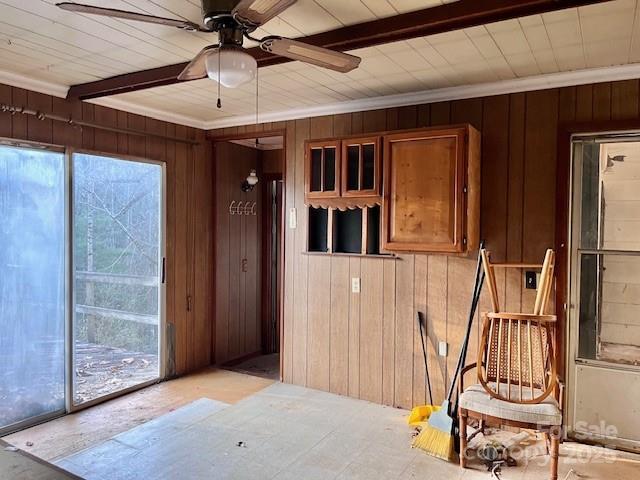 interior space featuring ceiling fan, wooden walls, and a wealth of natural light