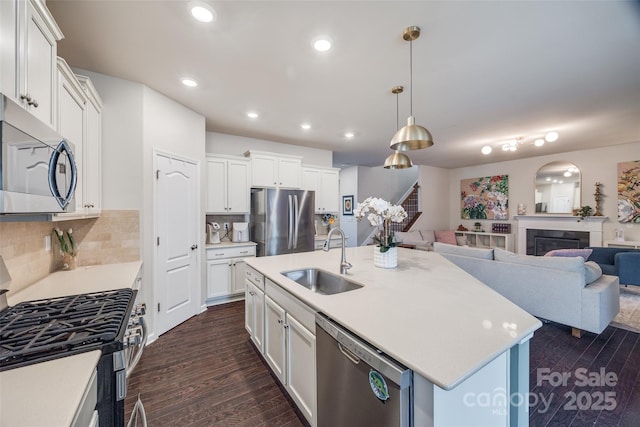 kitchen featuring white cabinetry, appliances with stainless steel finishes, sink, and a center island with sink