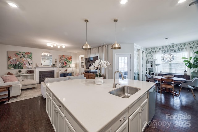 kitchen with pendant lighting, sink, dark wood-type flooring, a kitchen island with sink, and stainless steel dishwasher